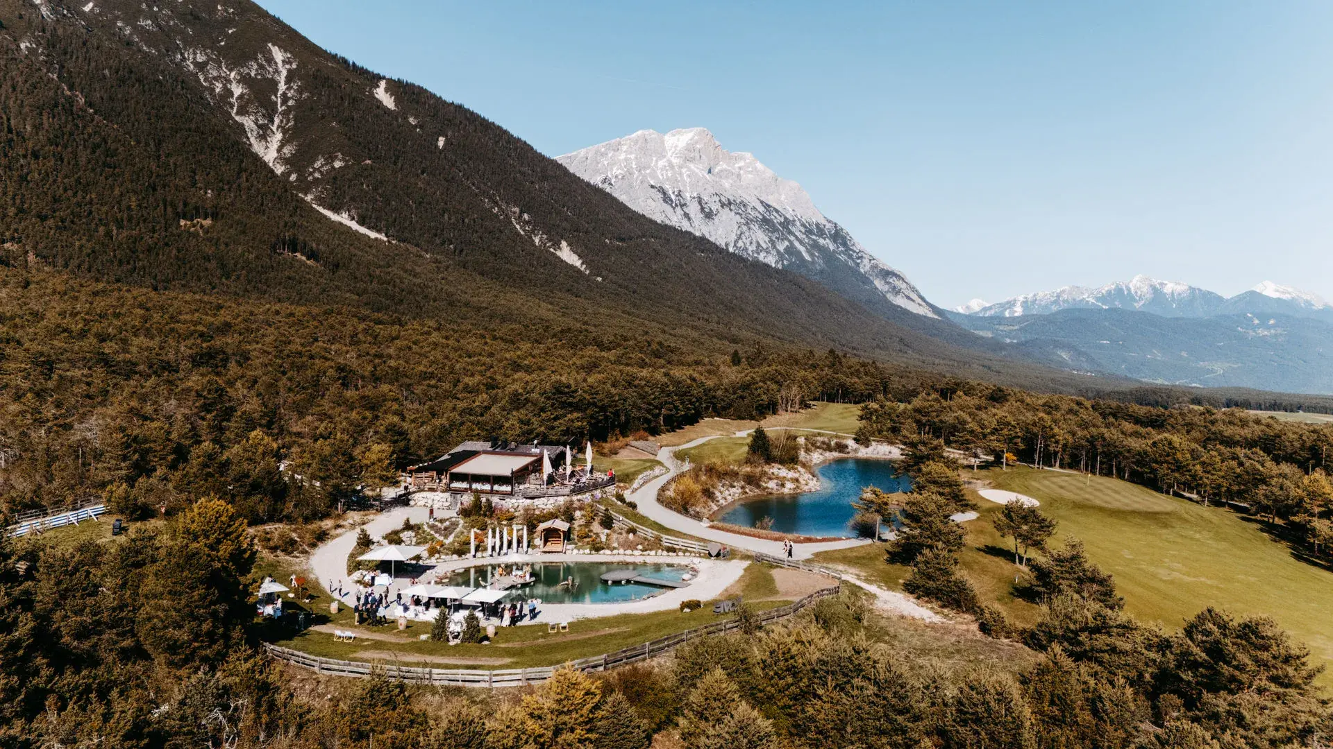 Aerial view of the Stöttlalm with its bathing pond below the snow-capped Mieminger Kette in Tyrol