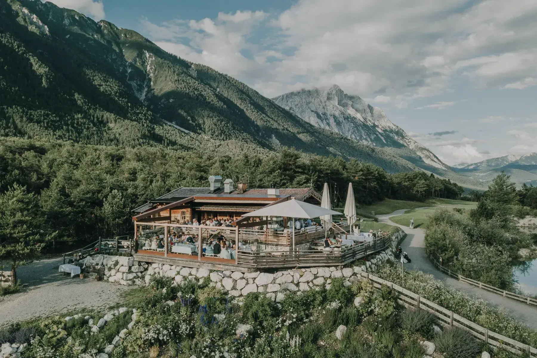 Stöttlalm alpine hut with its covered wooden sun terrace on a green knoll before the Mieminger Kette in Tyrol