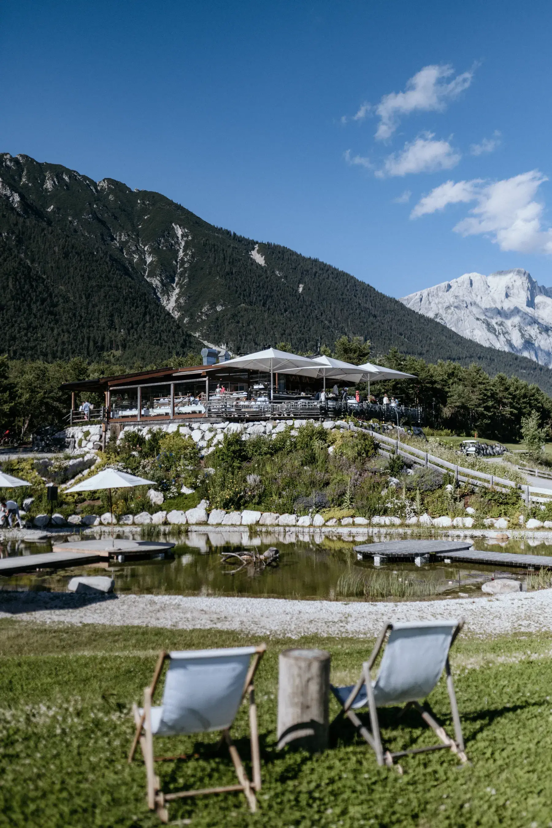 Covered sun terrace of the Stöttlalm above the Stöttlalmsee, with deck chairs and the Mieminger Kette behind